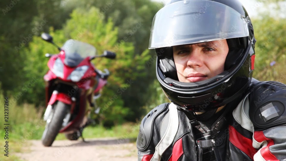 Biker sits near motorcycle, see and close visor on it helmet Biker sits near motorcycle, see and close visor on it helmet