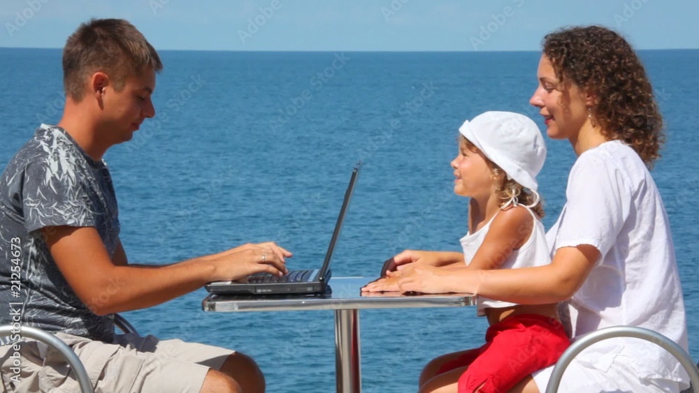family of three persons with notebook sits at table family of three persons with notebook sits at table