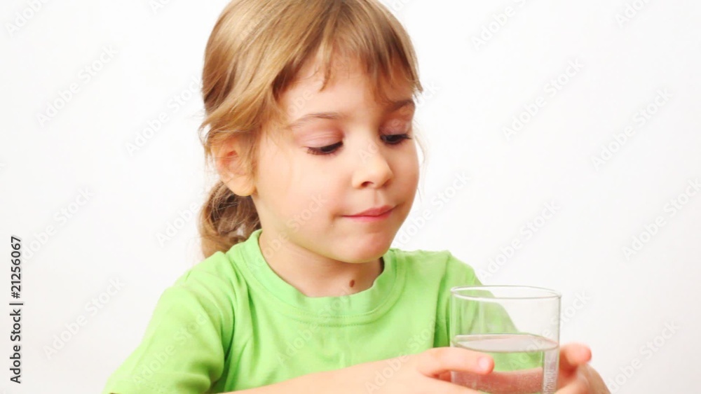 small girl drinks water from glass and smiles on white small girl drinks water from glass and smiles on white