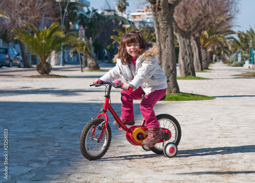 Smiling little girl rideng a bisycle photo