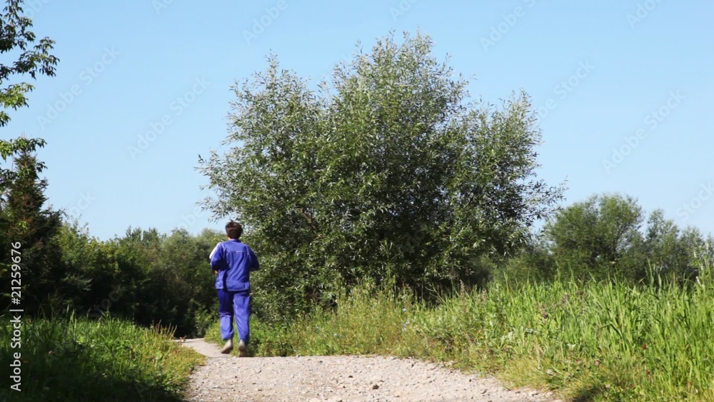 man in turn blue gym suits runs back on lane in park in summer man in turn blue gym suits runs back on lane in park in summer