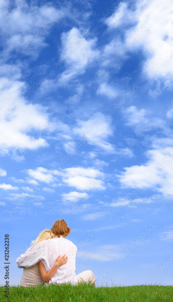 Guy and girl sitting on the ground beneath the cloudy sky