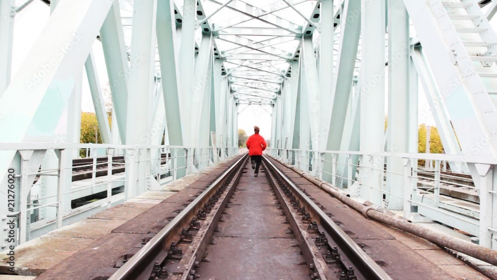 red-haired young man runs forward on camera on railway bridge red-haired young man runs forward on camera on railway bridge