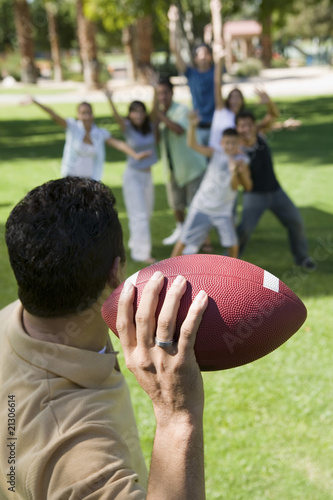 man throwing football to group of people back view.