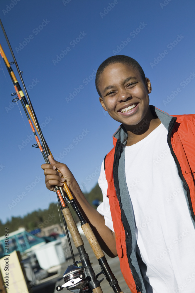 boy holding fishing rod smiling (portrait) boy holding fishing rod smiling (portrait)