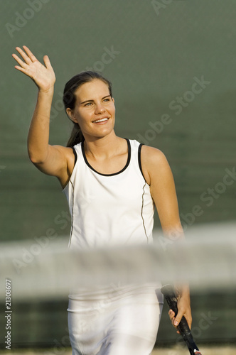 tennis player standing near net arm raised and waving