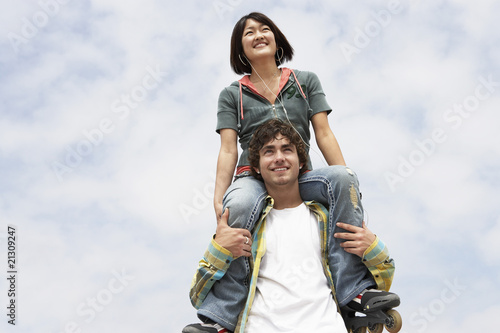young woman on shoulders of man low angle view