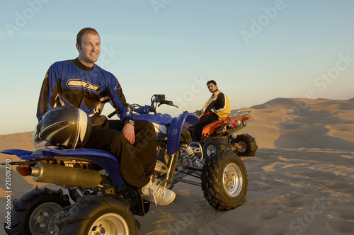 men standing by quad bikes in desert