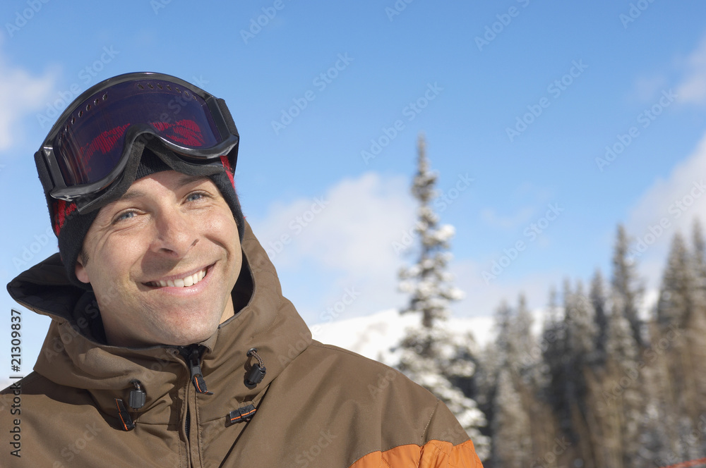 young man wearing ski goggles on head in snow portrait. young man wearing ski goggles on head in snow portrait.