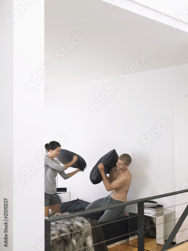 couple on bed having a pillow fight photo