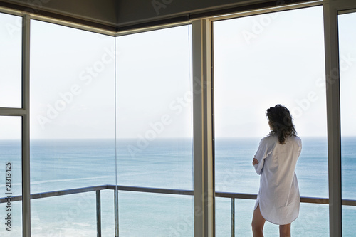 woman looking at view standing on balcony back view © moodboard