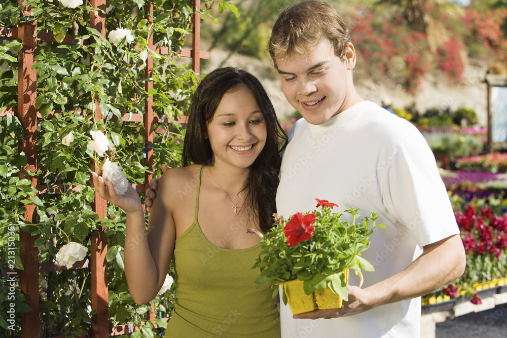 young couple choosing potted flowers in garden centre