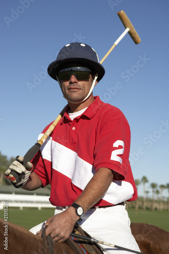 polo player holding polo stick on horseback on polo field
