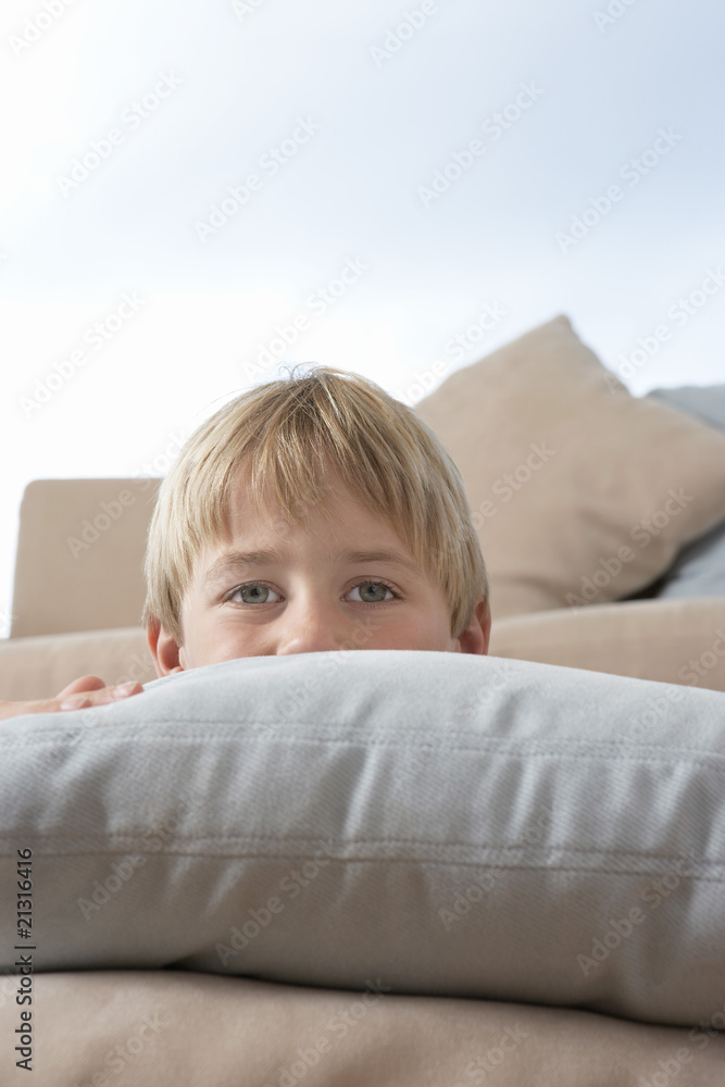 young boy hiding behind pillows and cushions young boy hiding behind pillows and cushions