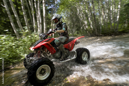 Female riding ATV through creek