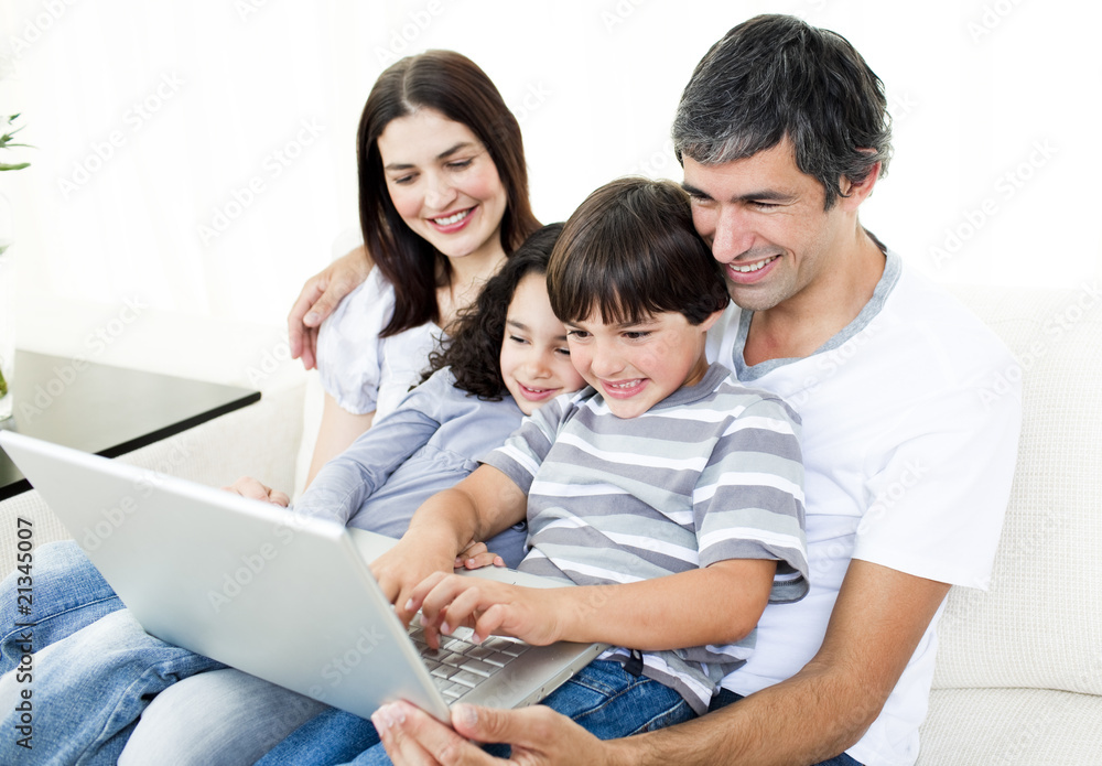 Glad family using a laptop sitting on sofa Glad family using a laptop sitting on sofa