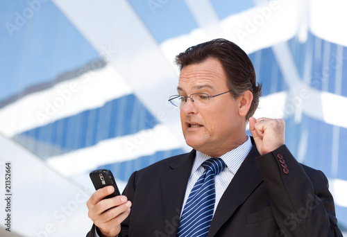 Businessman Looking at Cell Phone Clinches His Fist in Joy photo