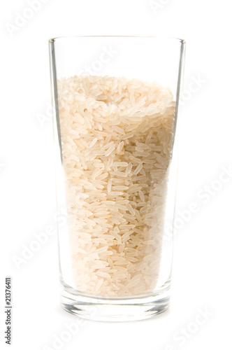Dry rice in a transparent glass on a white background