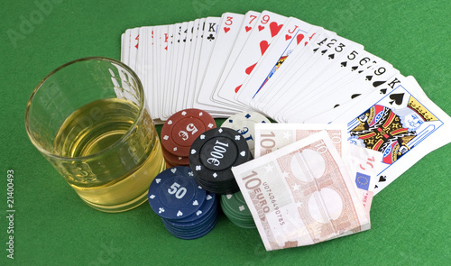 Fotografía baraja y fichas de poker junto a vaso de whisky y billete