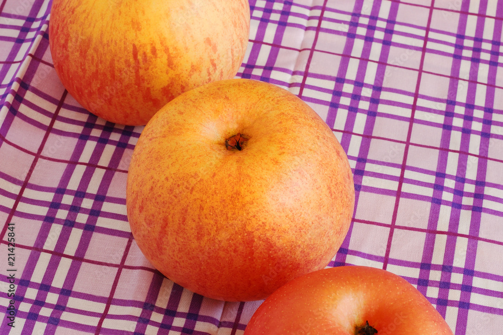 Ripe appetizing  apples on purple-white stripy tablecloth