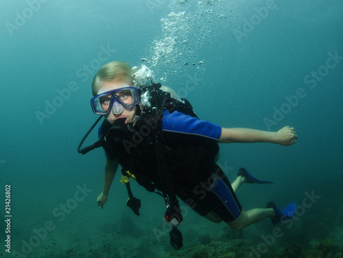 female scuba diver swimming over coral reef