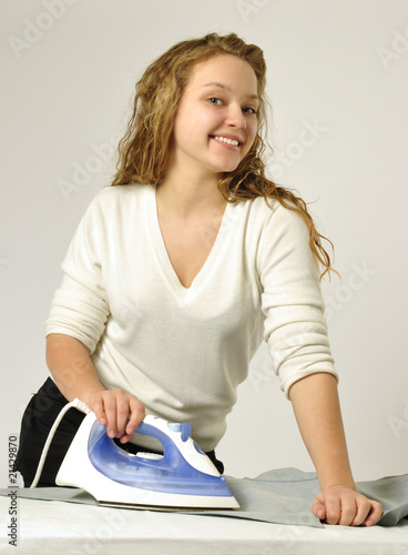 Portrait of beautiful young housewife ironing