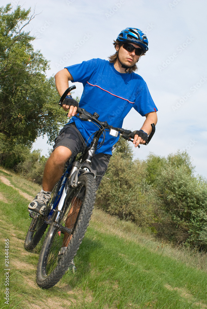 young bicyclist in a blue helmet on nature