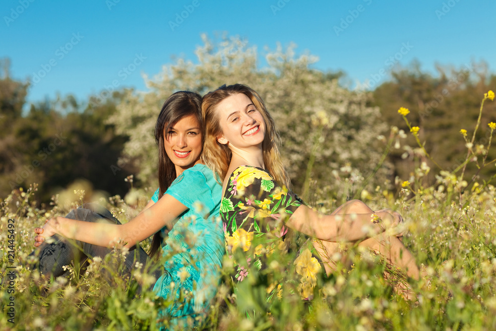 Two beautiful young women sitting in blooming meadow Two beautiful young women sitting in blooming meadow
