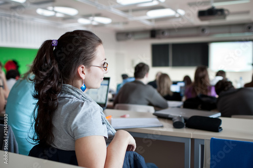 young pretty female college student sitting in a classroom full