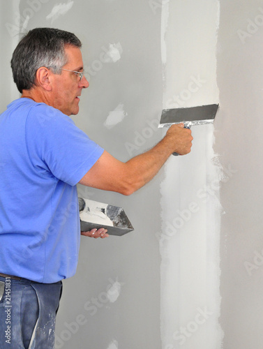 Man using trowel to finish seam between drywall panels