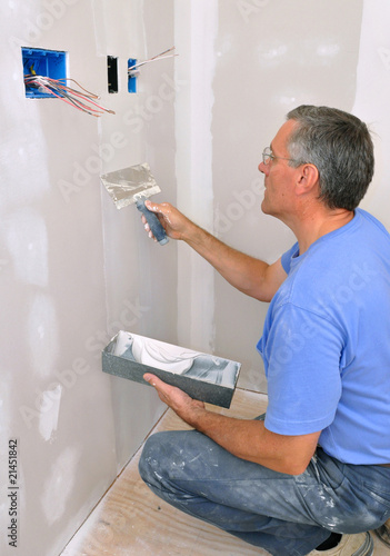 Man using drywall knife to finish seam between drywall sheets