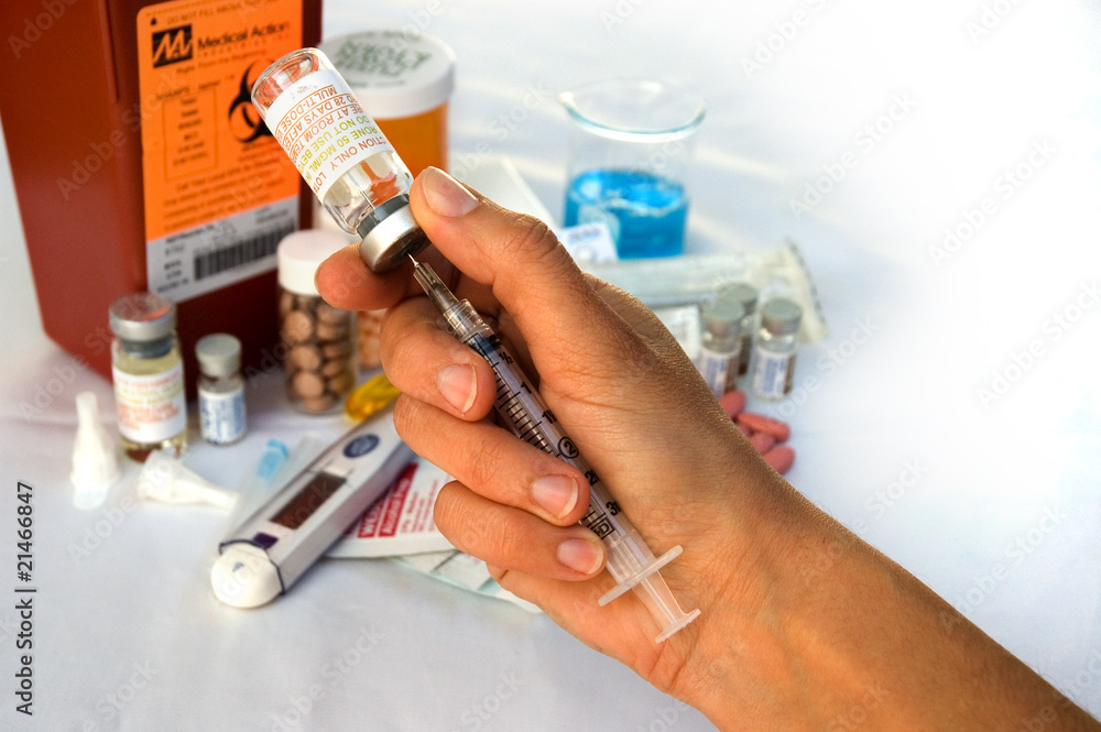 Hand holding a syringe infront of fertility medical supplies Hand holding a syringe infront of fertility medical supplies