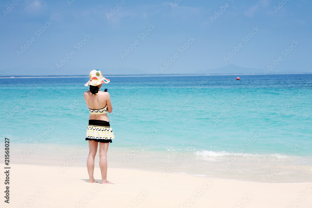 A beautiful woman wearing a bikini facing the sea A beautiful woman wearing a bikini facing the sea