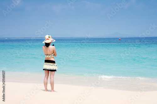 A beautiful woman wearing a bikini facing the sea