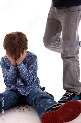 child crying on the floor being kicked by a teenager