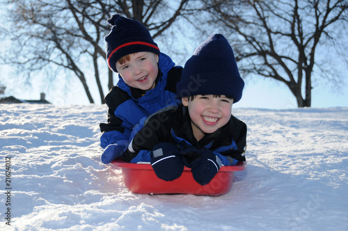 Photography Two young boys sledding downhill together