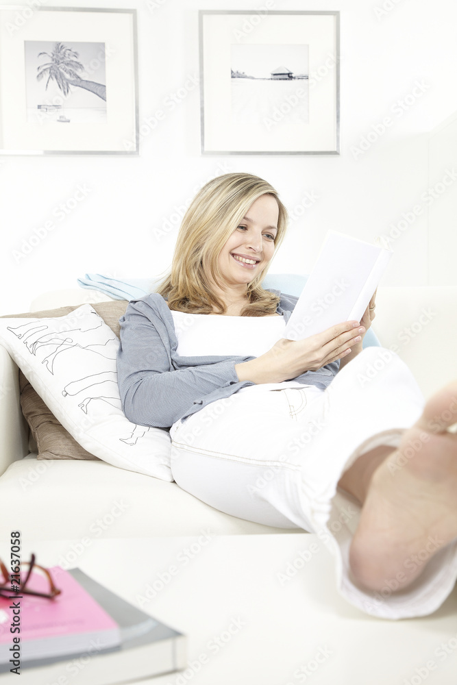 junge frau sitzt auf sofa und liest ein buch junge frau sitzt auf sofa und liest ein buch