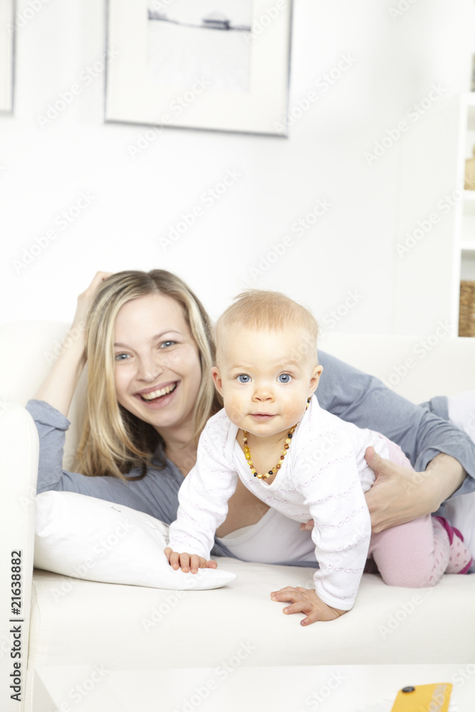 junge mutter mit baby auf weißem sofa junge mutter mit baby auf weißem sofa