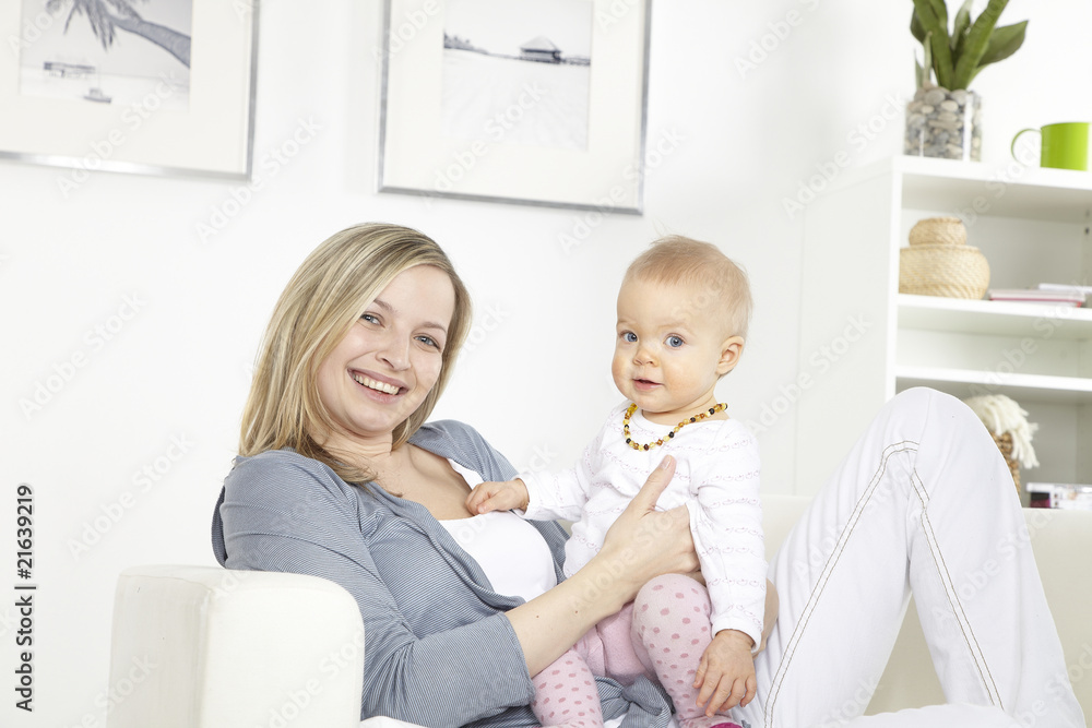 junge mutter mit baby auf weißem sofa junge mutter mit baby auf weißem sofa