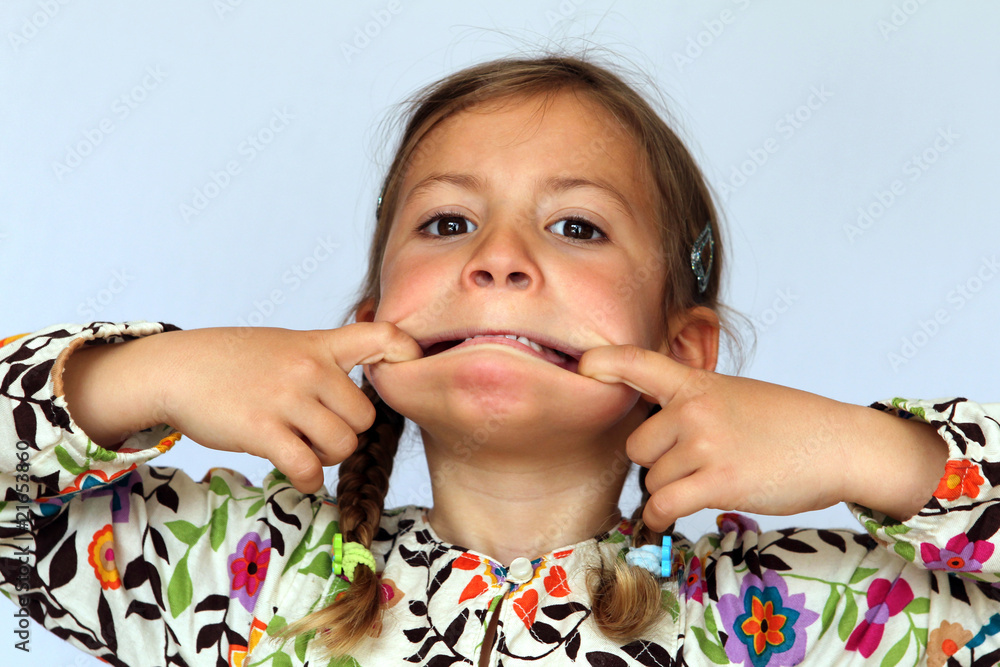 Studio portrait of young girl pulling her mouth open Stock 사진 Adobe Stock