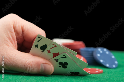 Fotografía an adult man playing poker . Close-uo of hand. Three sevens