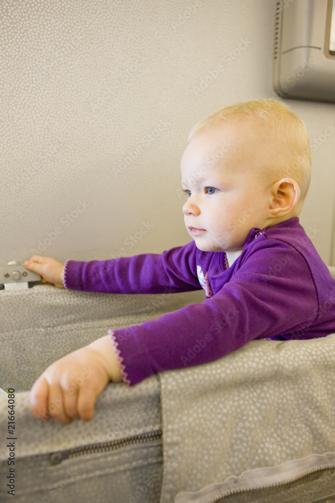 Naklejka premium sitting toddler girl travelling by plane