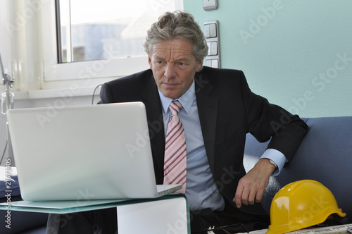 Mann mit Bauhelm am PC