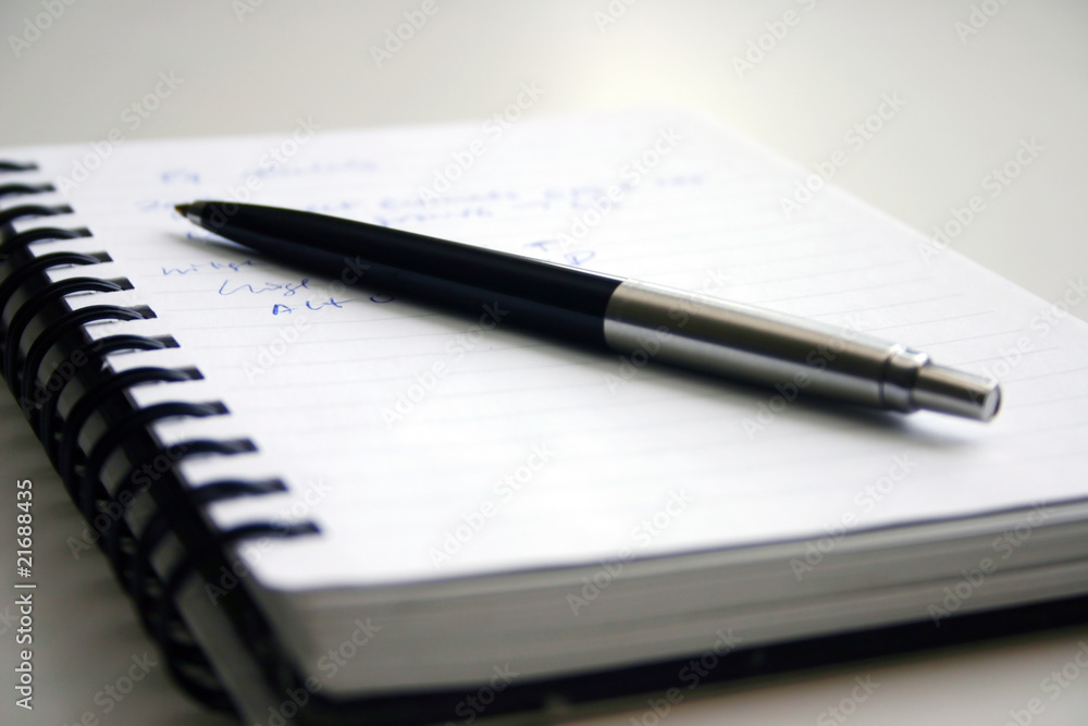 A black pen and notebook with words. A black pen and notebook with words.
