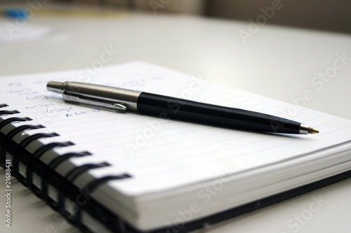 A notbook and black pen on the table.