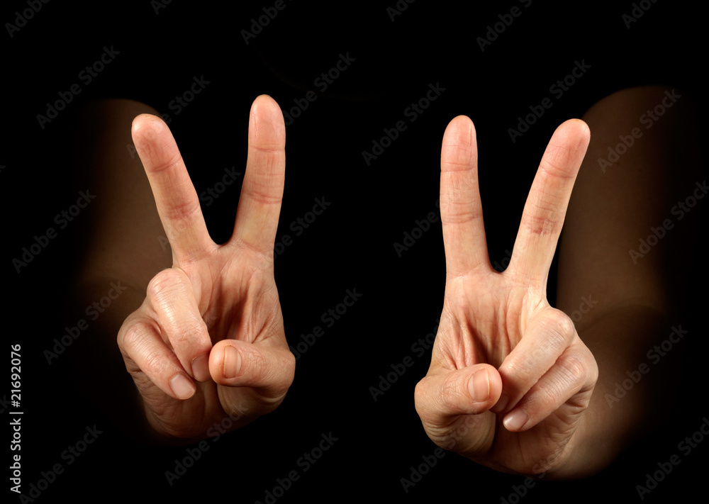 Woman hands showing victory on black background Woman hands showing victory on black background