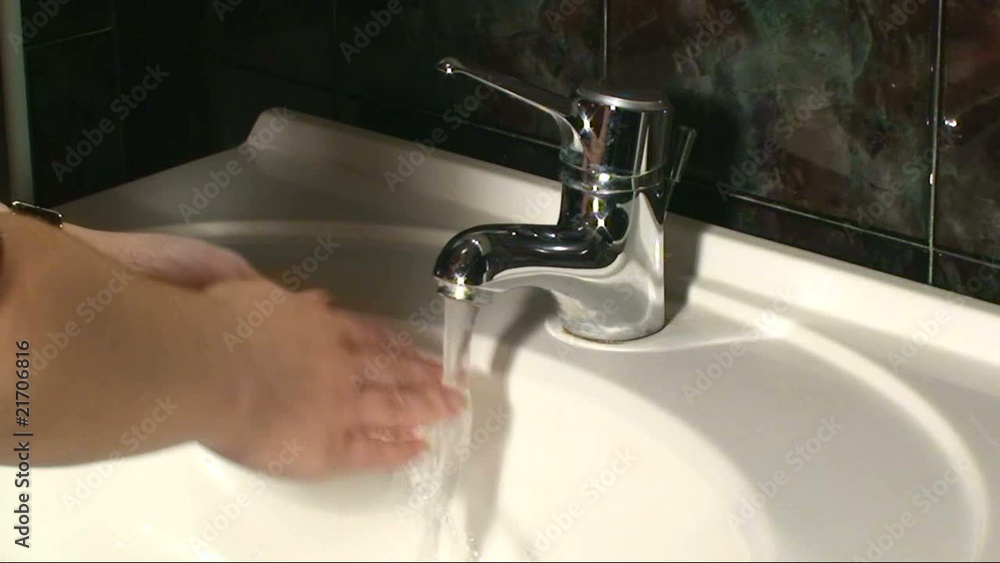 Woman's hand starting and stopping tap water in bathroom Woman's hand starting and stopping tap water in bathroom