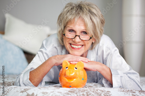 Konstfotografi moderne ältere dame mit sparschwein zuhause
