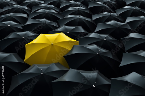 Yellow umbrella among black umbrellas photo