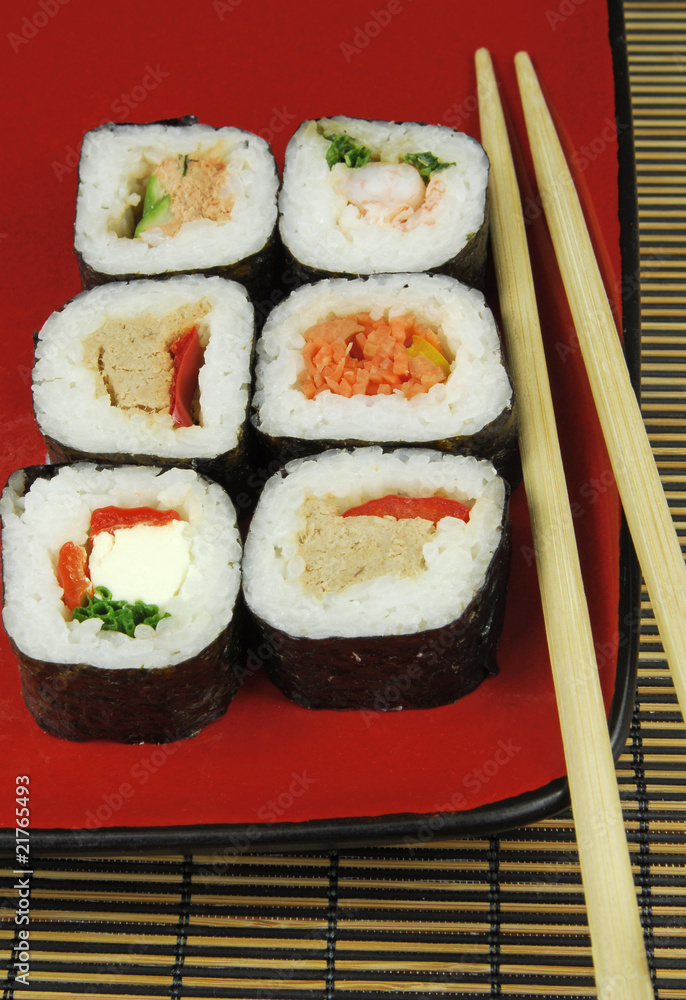 sushi futomaki on red plate with chopsticks sushi futomaki on red plate with chopsticks